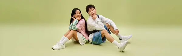 A couple playfully poses in a pastel background, showcasing their love and fashion. — Stock Photo