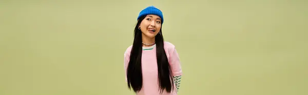 Beautiful trendy woman in vibrant outfit posing cheerfully on pastel backdrop. — Stock Photo