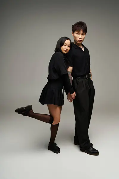 Um casal elegante está de mãos dadas, mostrando suas roupas pretas chiques e carinho. — Fotografia de Stock