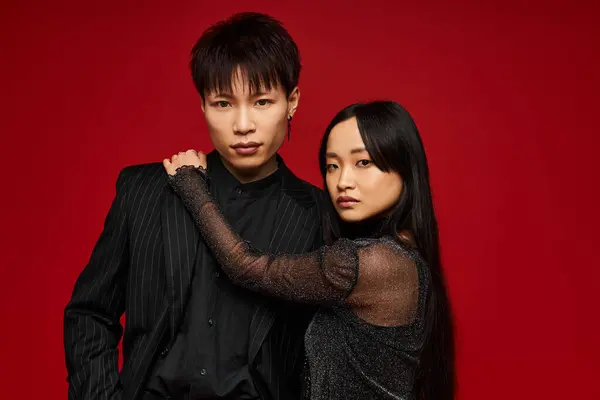 A stylish couple radiates love and confidence against a bold red backdrop. — Stock Photo