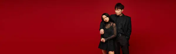 Fashionable couple showcases elegance and charm, embodying romance in a striking red setting. — Stock Photo