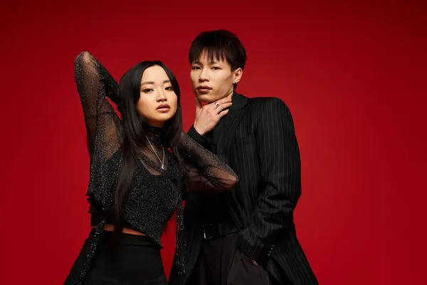 A couple showcases their love and style against a bold red backdrop. — Stock Photo