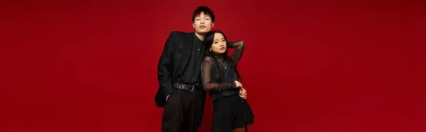 Un couple élégant rayonne de romance dans un fond rouge audacieux, mettant en valeur leur mode. — Photo de stock