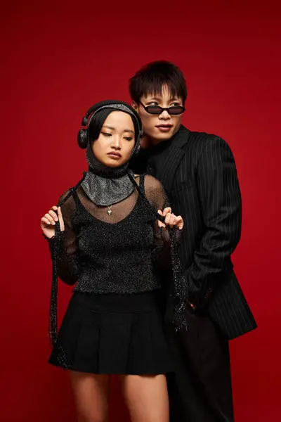 Um casal elegante mostra seu romance com poses e roupas contra um cenário vermelho vívido. — Fotografia de Stock