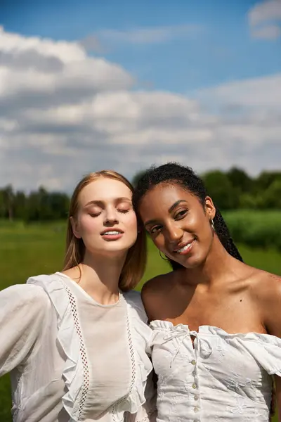 Two women share a loving moment in a lush field under a bright sky. — Stock Photo