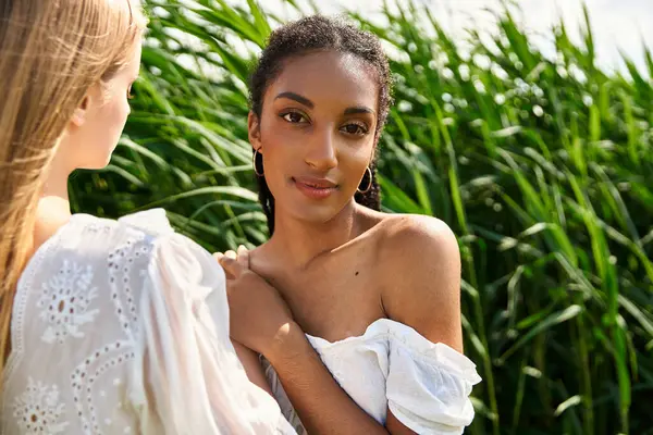 Two women share a moment of tenderness in a vibrant green field, celebrating their connection. — Stock Photo