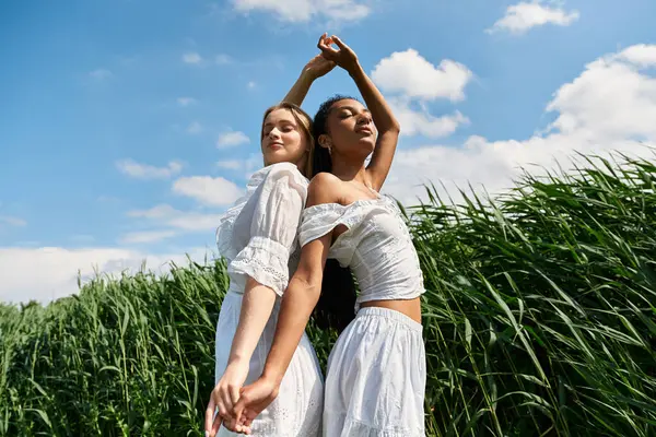 Two beautiful women share a loving embrace, showcasing their connection in a vibrant green field. — Stock Photo