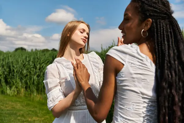 Two young women express their love and joy in a lush green field under a bright sky. — Stock Photo