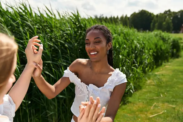 Two joyful women connect in a sunny green field, sharing laughter and warmth. — Stock Photo