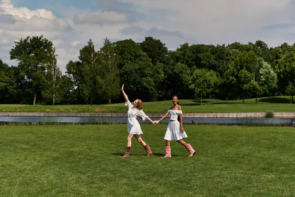 Dos jóvenes bailan alegremente en un exuberante parque, celebrando su amor bajo un cielo despejado. - foto de stock