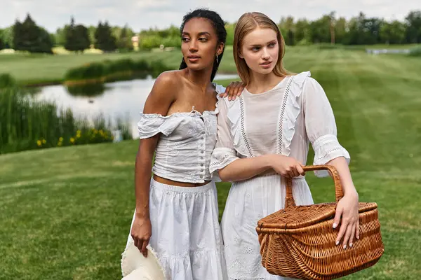 Two young women share a loving moment while preparing for a picnic in a vibrant park. — Stock Photo