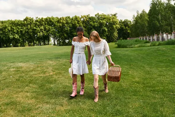 Young women walk hand in hand, enjoying nature and their love in a vibrant green park. — Stock Photo