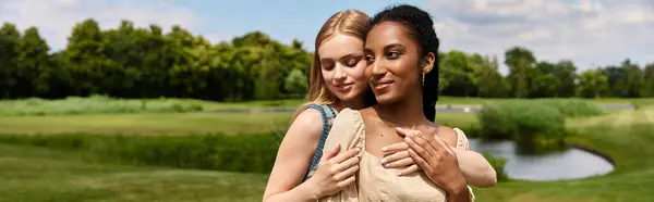 Two young women share a tender moment together in a lush green park, radiating joy and love. — Stock Photo