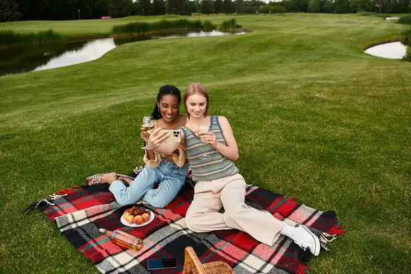 Duas mulheres jovens desfrutar de um piquenique ensolarado, saboreando lanches saborosos e companhia uns dos outros. — Fotografia de Stock