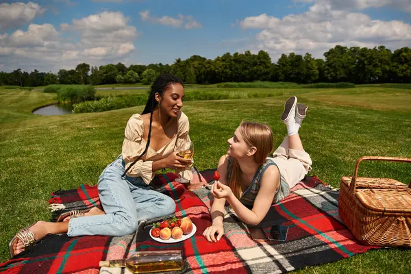Two women share laughter and love while having a picnic together on a lush green field. — Stock Photo
