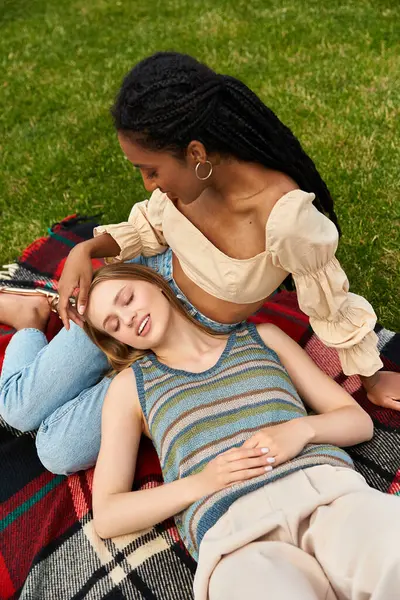 Two young women relax on a colorful blanket, enjoying their joyful bond in the park. — Stock Photo