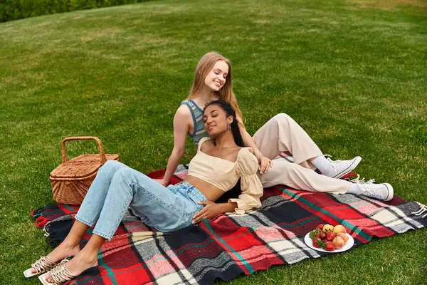 A lovely lesbian couple relaxes on a blanket, laughing and enjoying nature together. — Stock Photo
