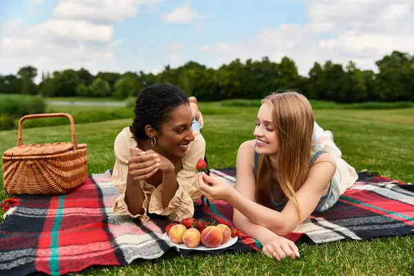 Two beautiful women share joyful moments while savoring fresh fruits during a lovely picnic. — Stock Photo