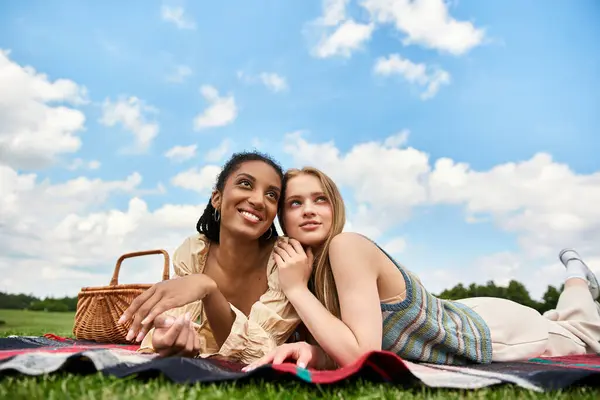 Joyful young women relax on a blanket, sharing laughter and love while picnicking outdoors — Stock Photo