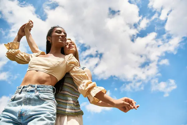 Two young women embrace joyfully while dancing outdoors in a sunny setting. — Stock Photo