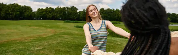 Two women embrace in a beautiful park, radiating love and joy under a bright blue sky. — Stock Photo