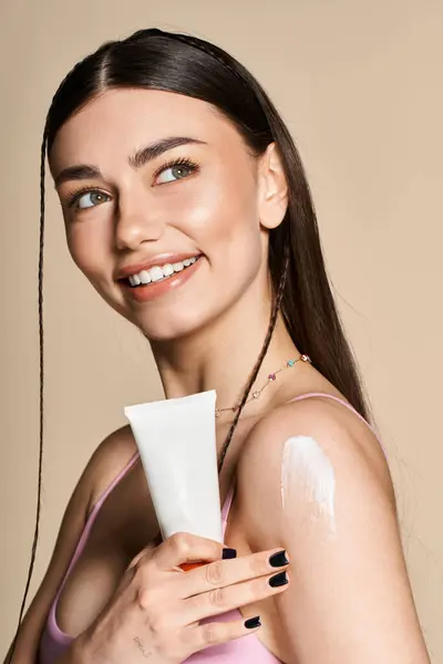 A vibrant young woman applies sunscreen with a radiant smile, embodying summer joy and self-care. — Stock Photo