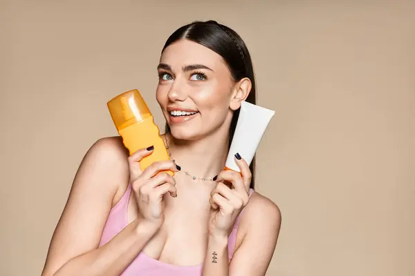 Joyful young woman holds sunscreen products, emphasizing summer fun and sun protection. — Stock Photo