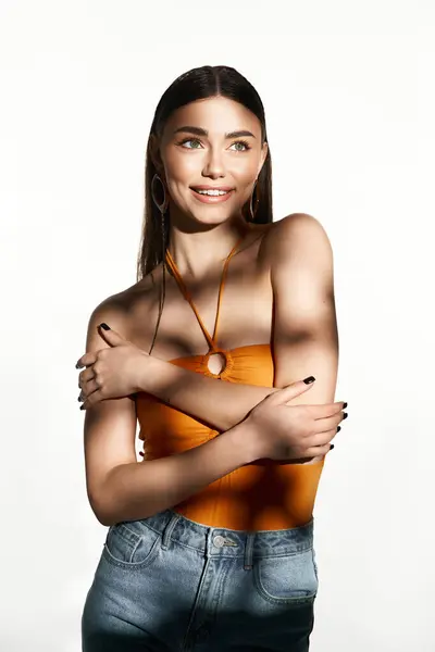 Une jeune femme dans un haut orange élégant embrasse la joie de l'été tout en montrant sa peau embrassée par le soleil. — Photo de stock