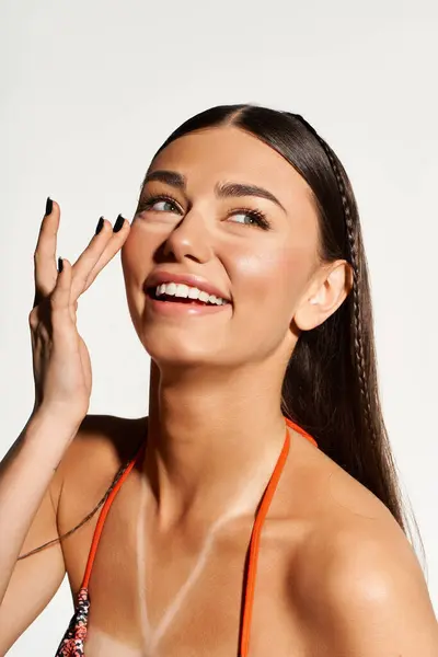 A young woman with a sun tan applies sunscreen while smiling joyfully during summer fun. — Stock Photo