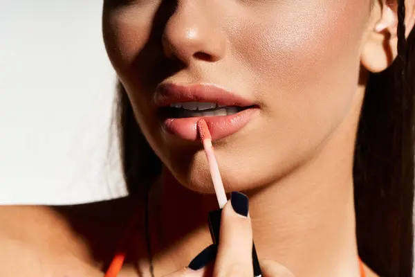 A young woman enjoying summer sun while applying lip gloss to enhance her sun-kissed look. — Stock Photo