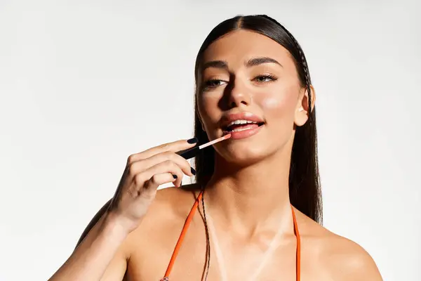 This young woman applies lip gloss, her sun-kissed skin reflecting the joy of summer days ahead. — Stock Photo