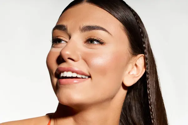 Mujer joven con un bronceado muestra una sonrisa alegre, abrazando el calor y el resplandor del verano. - foto de stock