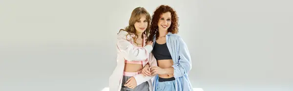 Duas jovens mulheres abraçam-se alegremente em um estúdio elegante. — Fotografia de Stock