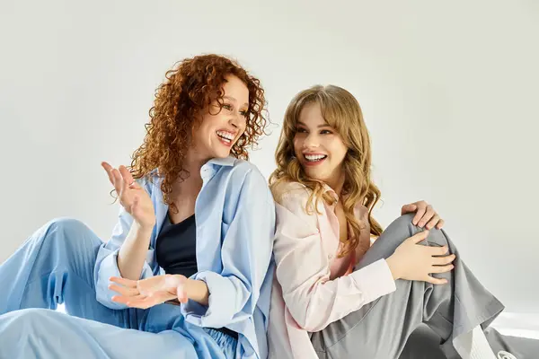 A young loving lesbian couple sits close, smiling and sharing laughter in a cozy indoor space. — Stock Photo