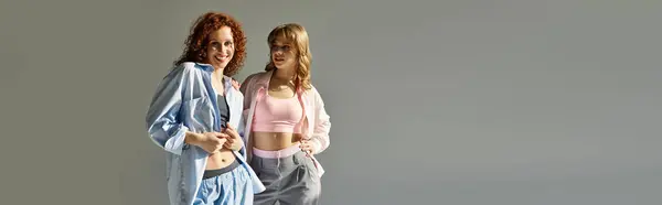 Zwei junge Frauen lächeln sich freudig an und zeigen ihre Zuneigung in einem sanft beleuchteten Studio. — Stockfoto