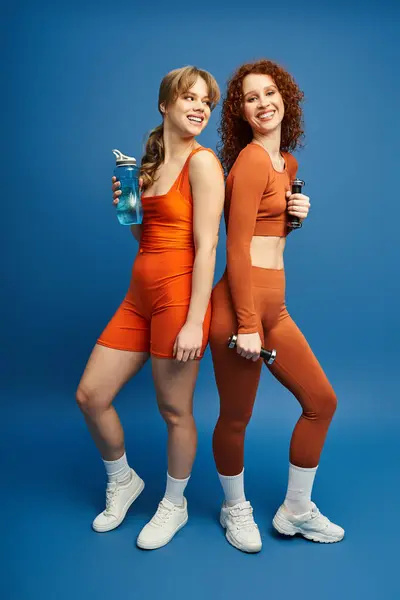 Two young women sharing a joyful moment while exercising together, radiating love and energy — Stock Photo