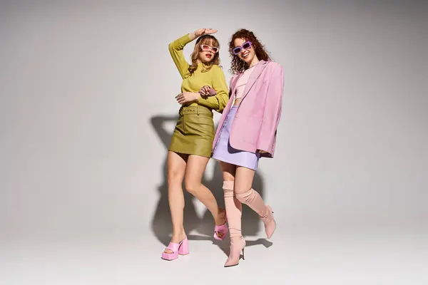 Two young women joyfully celebrate fashion and love in a bright, playful setting. — Stock Photo