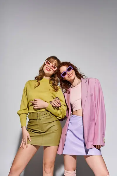 Two young women show affection playfully in trendy outfits under soft lighting. — Stock Photo