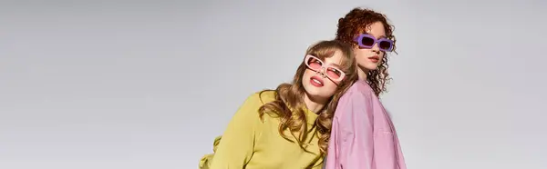 Two women share a stylish, colorful moment, highlighting their bond and fun accessories. — Stock Photo