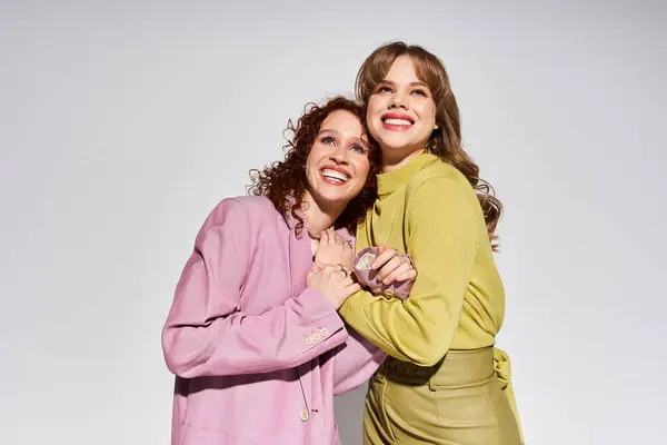 Two young women share a loving moment, smiling warmly while holding hands, wearing stylish outfits. — Stock Photo
