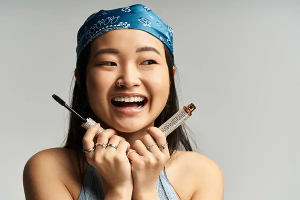 A young Asian woman beams joyfully as she playfully shows her makeup tools. — Stock Photo