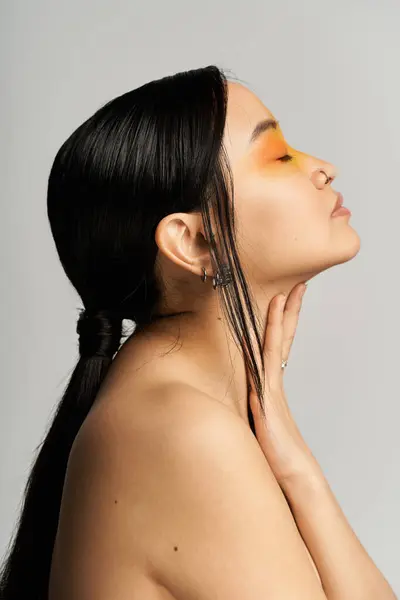 A beautiful young Asian woman poses elegantly, showcasing her striking makeup artistry. — Stock Photo