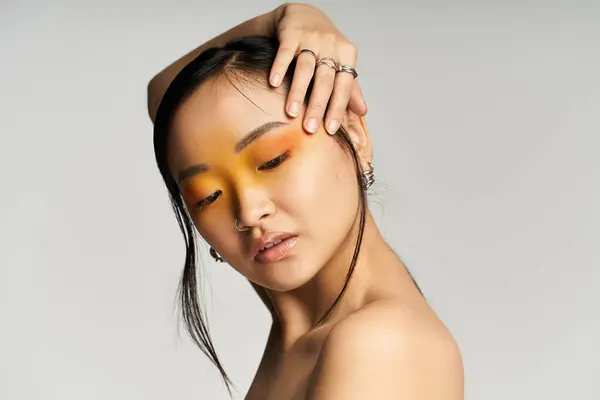 A young Asian woman poses gracefully, confidence shining through her stunning orange makeup. — Stock Photo