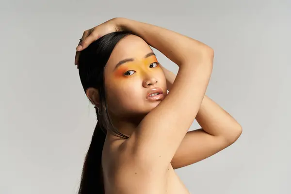 Young beautiful woman showcases artistic makeup with bold colors, posing gracefully in a studio. — Stock Photo