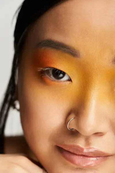 A young beautiful asian woman showcases her vibrant makeup while gazing thoughtfully at the viewer. — Stock Photo