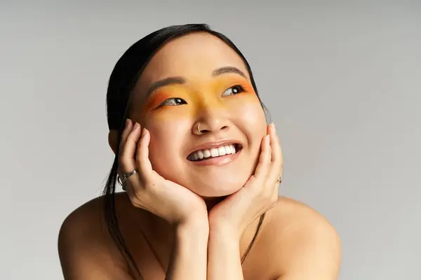 Joyful young Asian woman showcases her artistic makeup in soft, flattering lighting. — Stock Photo