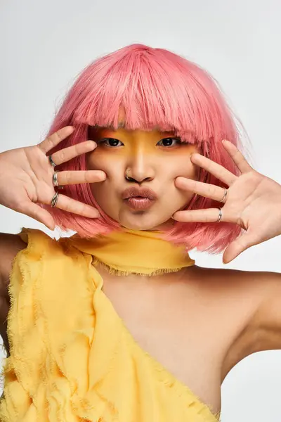 Una giovane donna asiatica mostra il suo lato giocoso con i capelli rosa vivaci e il trucco giallo audace. — Foto stock