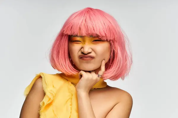 Joven mujer asiática con pelo rosa vibrante y maquillaje audaz posa juguetonamente. - foto de stock