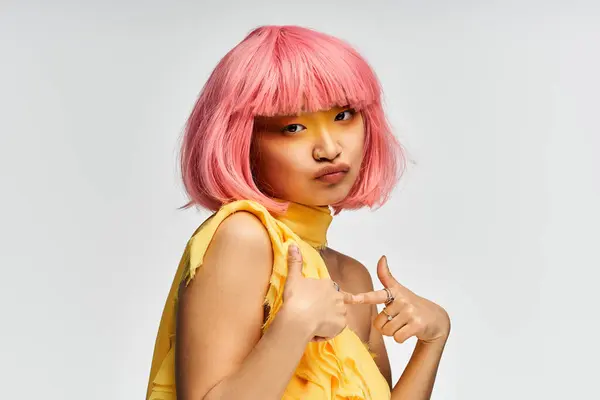 Brightly colored hair shines as the young woman poses playfully in a stunning yellow outfit. — Stock Photo