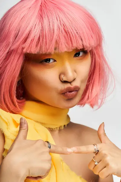 Vibrant young woman with pink hair showcases her playful spirit while dressed in yellow hues. — Stock Photo
